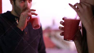 Young man and woman toasting and drinking fruit smoothie