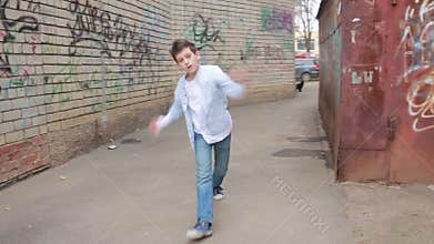 Teen boy dancing, street dancing on the background of brick wall
