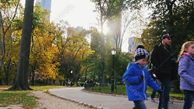New York, USA - OKT, 2016: People walking along the alley in Central Park in NYC. Sun get behind the skyscrapers