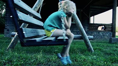 The little girl is upset on the swings. offense
