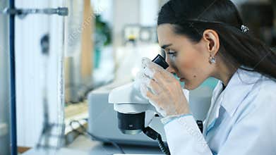Beautiful woman in a laboratory working with a microscope