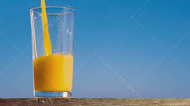 Pouring a glass of orange juice creating splash