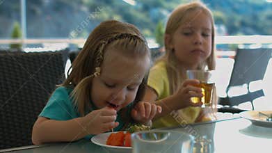 Two little sisters eating in the cafe