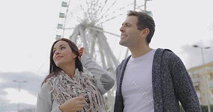 Young couple standing in front of a ferris wheel