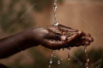 Social Issues: Water Pouring in African Child`s Hands