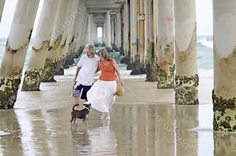 Senior man and woman enjoying a romantic relaxing holiday at beach with pet dog
