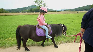 Little girl riding a pony in countryside