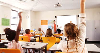 School kids raising hand in classroom