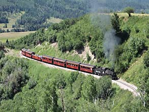 An historic coal fed passenger train wending its way through a mountain pass