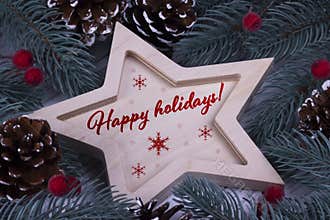 Christmas New Year Holiday greeting card with wooden five pointed star fir branches cones red berries and text Happy Holidays