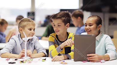 Kids with tablet pc programming at robotics school