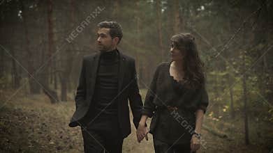 Close up of happy man and woman together walking on the path in the forest. Smiling couple are strolling among the