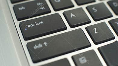 Female hand pressing caps lock button on keyboard to make typing letters capital