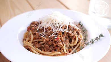 Female hands putting a plate of bolognese pasta with parmesan cheese decorated with rosemary on the desk 4K slowmo