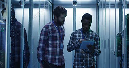 Diverse IT specialists with tablet in server room