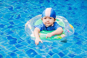 One little girls swimming in the pool with rubber ring, having f