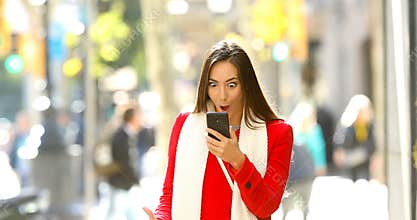 Shocked woman reading online news in the street