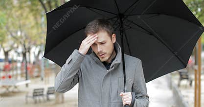 Man suffering head ache under the rain