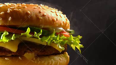 Giant delicious fresh burger rotating on dark smoke background. Cheeseburger macro view. American fastfood, unhealthy
