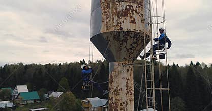 Industrial climbers paint the iron tower. Risky job. Extreme work. Worker alpinist.