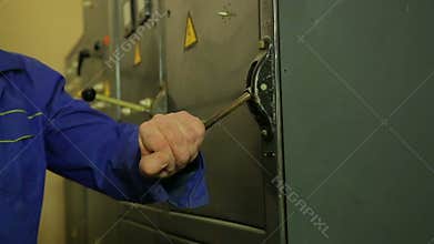 The hand of an electrician engineer turns off the electrical panel