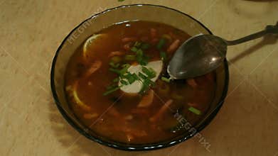 Male hands pour hodgepodge soup in a bowl. Solyanka. Russian cuisine.
