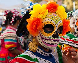 Woman wearing colorful skull mask and paper flowers for Dia de Los Muertos/Day of the Dead