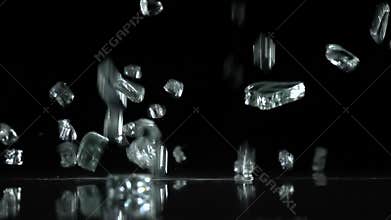 Broken glass falls to the floor. Black background. Slow motion