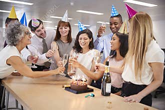 Colleagues celebrating a birthday in the office make a toast
