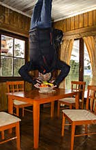 Unusual foreshortening of a man trying to eat fruit upside down