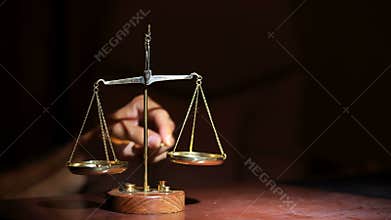 The hand puts the weights on the right side of the scales