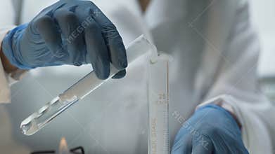 Lab researcher pouring experimental substance into tube, chemistry lesson
