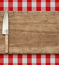 Cutting breadboard and kitchen knife. Cooking set over red gingham tablecloth.