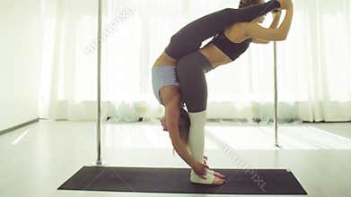 Two young women practicing acrobatic yoga.
