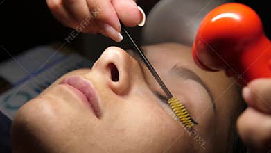 Beauty and fashion concept. Preparation for Eyelash Extension Procedure. Beautician prepares the eyelashes of a young