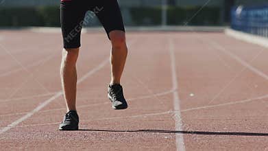 Sportsman warming up leg muscles at stadium for better blood circulation