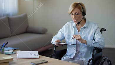 Travel agency consultant in wheelchair searching appropriate tour on tablet