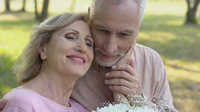 Senior couple on first date, man gives flowers to woman, mature love, romance