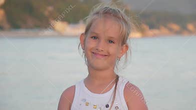 Portrait of little girl doing facial expressions and smiling, slow motion. Summer vacation.