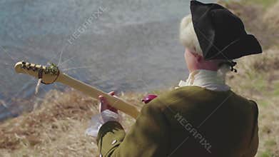 Aristocrat with a guitar on the lake. Stock. The concept of preserving classical music