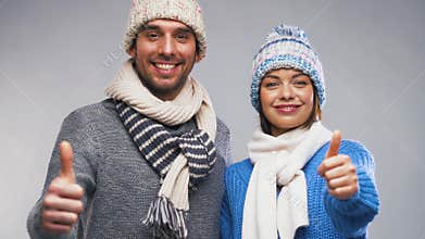 Happy couple in winter clothes showing thumbs up