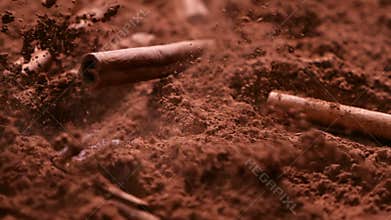 Cinnamon bars fall into cocoa powder - close up