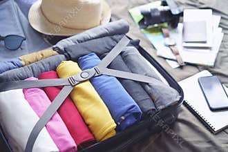 Prepare accessories for new journey and travel to long weekend trip, packing clothes in suitcase bag on bed