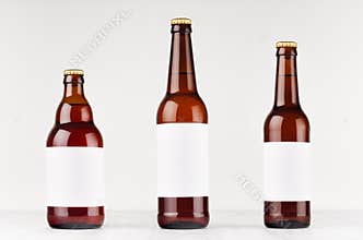 Brown beer bottles collection different type with blank white label on white wooden board, mock up.