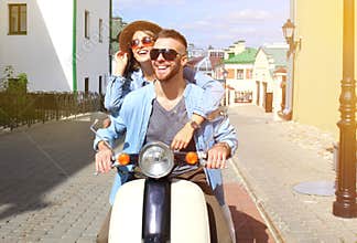 Happy young couple riding scooter in town. Handsome guy and young woman travel. Adventure and vacations concept.