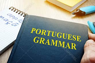 Learn portuguese grammar. Hand is holding book.