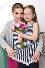 Happy Mother`s Day, Women`s day or Birthday background. Cute little girl giving mom, cancer survivor, bouquet of flowers.