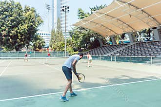 Rear view of a man ready to serve during doubles match