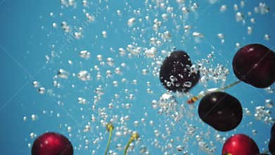 A fresh cherry are splashing into water on blue background.