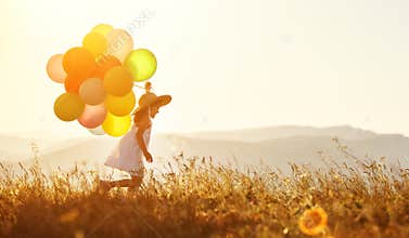 Happy child with balloons at sunset in summer